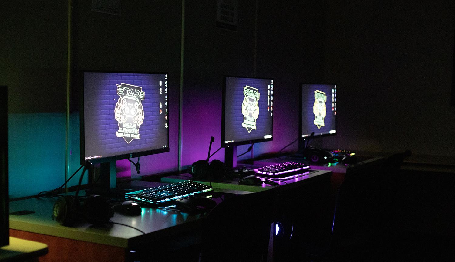 three desktop computer screens and backlit keyboards